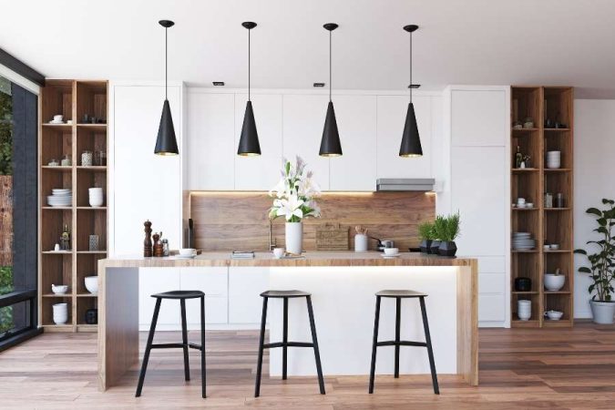 Une cuisine moderne lumineuse avec un îlot central en bois et des suspensions noires.
