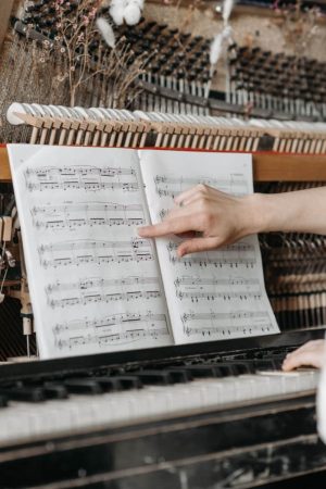 Une personne montre une partition de musique sur un piano droit, illustrant les techniques concrètes pour transmettre des émotions.
