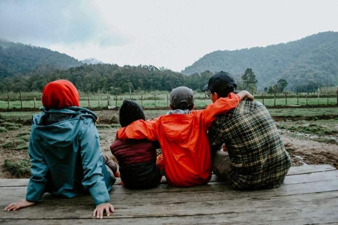Une famille profite d'une vue sur les montagnes, un moment paisible pour voyager en famille.